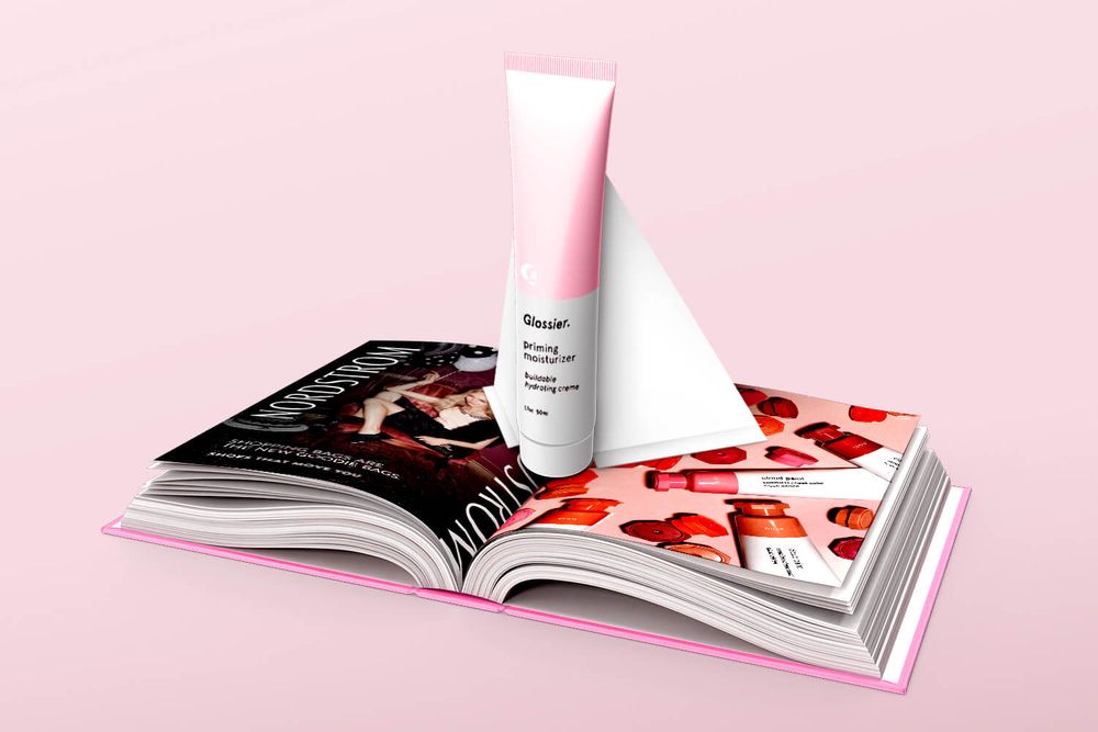 A Glossier moisturizer popping out of a magazine