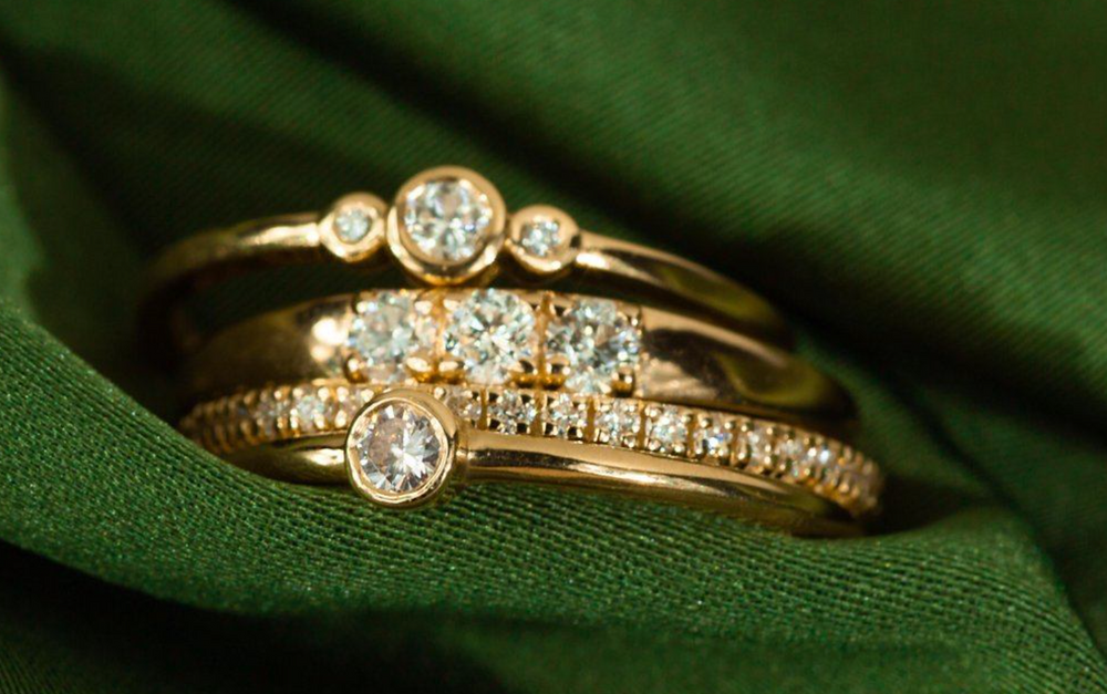 stack of Aurate diamond rings on a green background