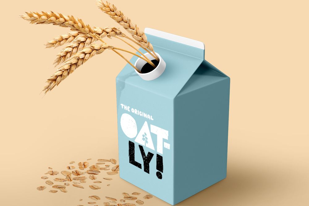 An illustration of Oatly's light blue oat milk carton. Some loose oats are scattered around its base, and a few oat stalks are sticking out of the hole at the top like it's a vase. 