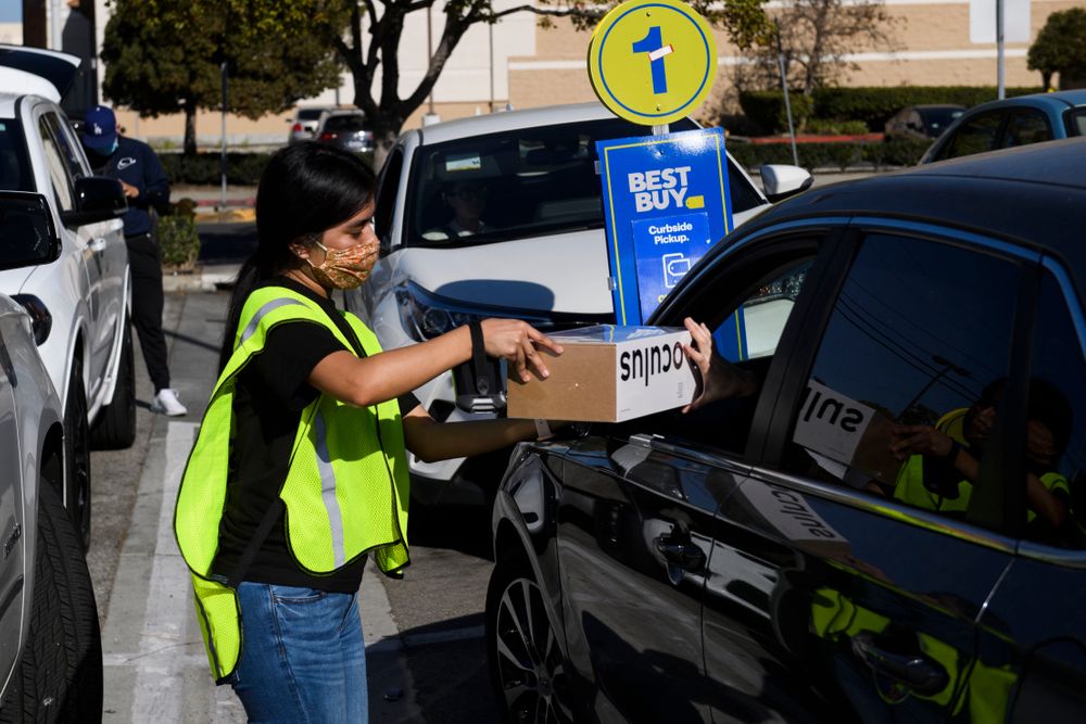 An employee delivers an Oculus VR headset curbside pickup order to a cus...