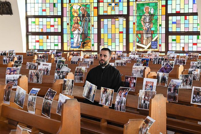 A priest prints out photos of his congregation for Easter mass service