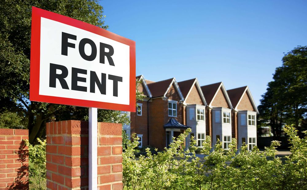 A "for rent" sign appears in front of a row of townhomes.