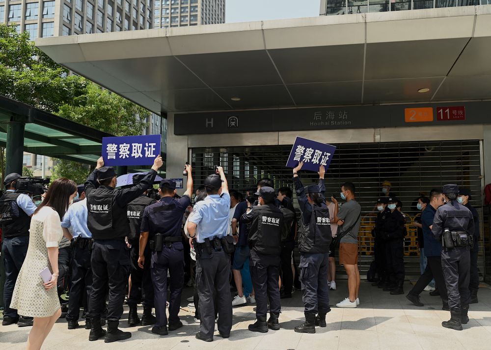 Police officers look at people gathering at the Evergrande headquarters ...