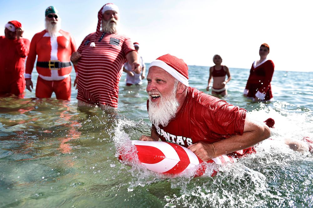 Actors dressed as Santa Claus take a refreshing bath at Bellevue Beach n...