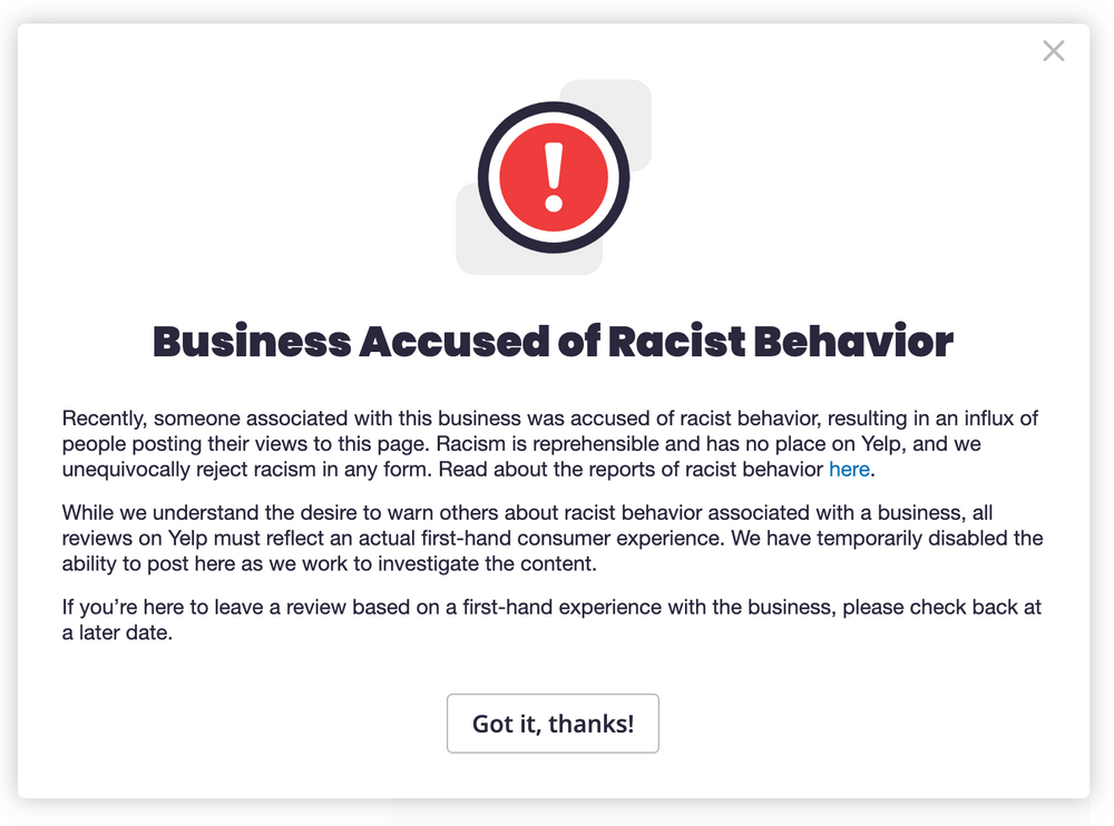 A photo of a Yelp website alert that states "Business Accused of Racist Behavior"