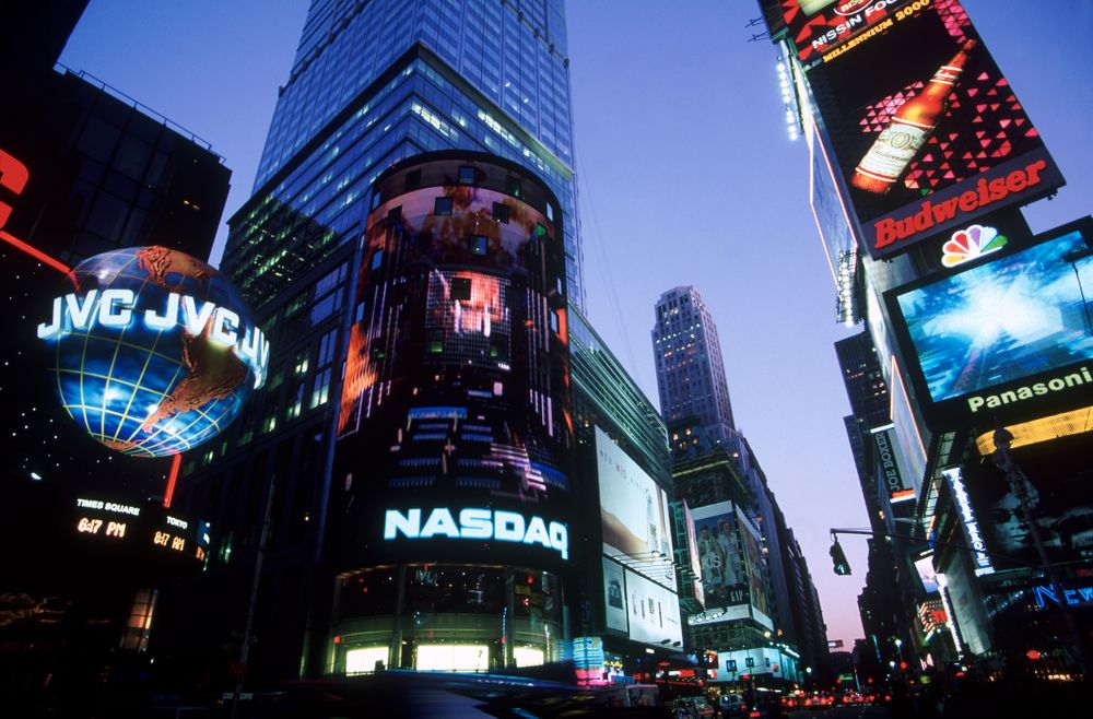 A photograph of the Nasdaq building lit up at night in Times Square.