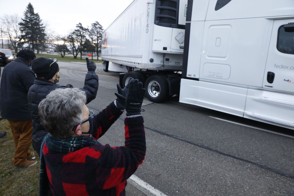 Nancy Galloway (L) and Susan Deur cheer as trucks carrying the first shipment of the Covid-19 vaccine that is being escorted by the US Marshals Service, leave Pfizer's Global Supply facility in Kalamazoo, MI.